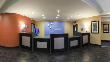 Zona de recepción con una pared azul, una recepcionista y un cartel que dice 'Hertz Express'.