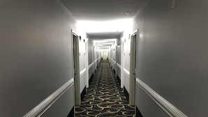 A long, narrow hotel hallway with a patterned carpet and doors on either side. - Express Inn (Weslaco)