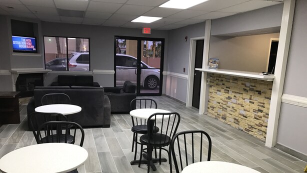 A restaurant interior with a seating area, tables, and a counter. - Express Inn (Weslaco)
