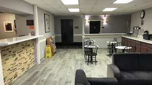 A modern interior with a reception desk, a black couch, and a dining area with chairs and tables. - Express Inn (Weslaco)