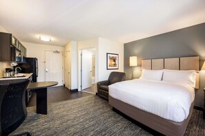 Une chambre d’hôtel avec un lit, un bureau, une chaise et une vue sur le couloir.