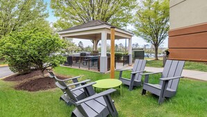 An outdoor patio with a gazebo, seating, and a grill area.