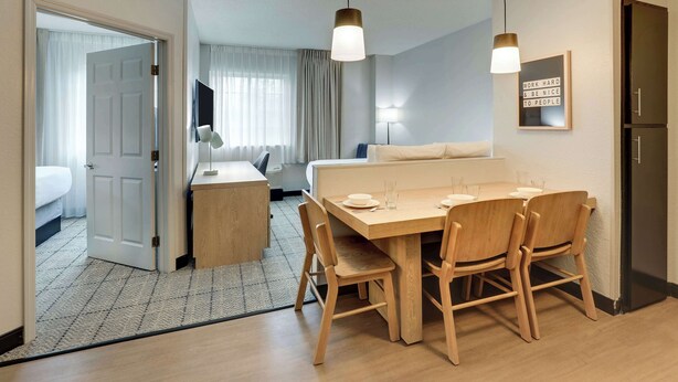 A hotel room with a dining area, a bed, a desk, and a wardrobe.