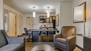 Una habitación de hotel moderna con comedor, cocina y una sala de estar con sillones de cuero.