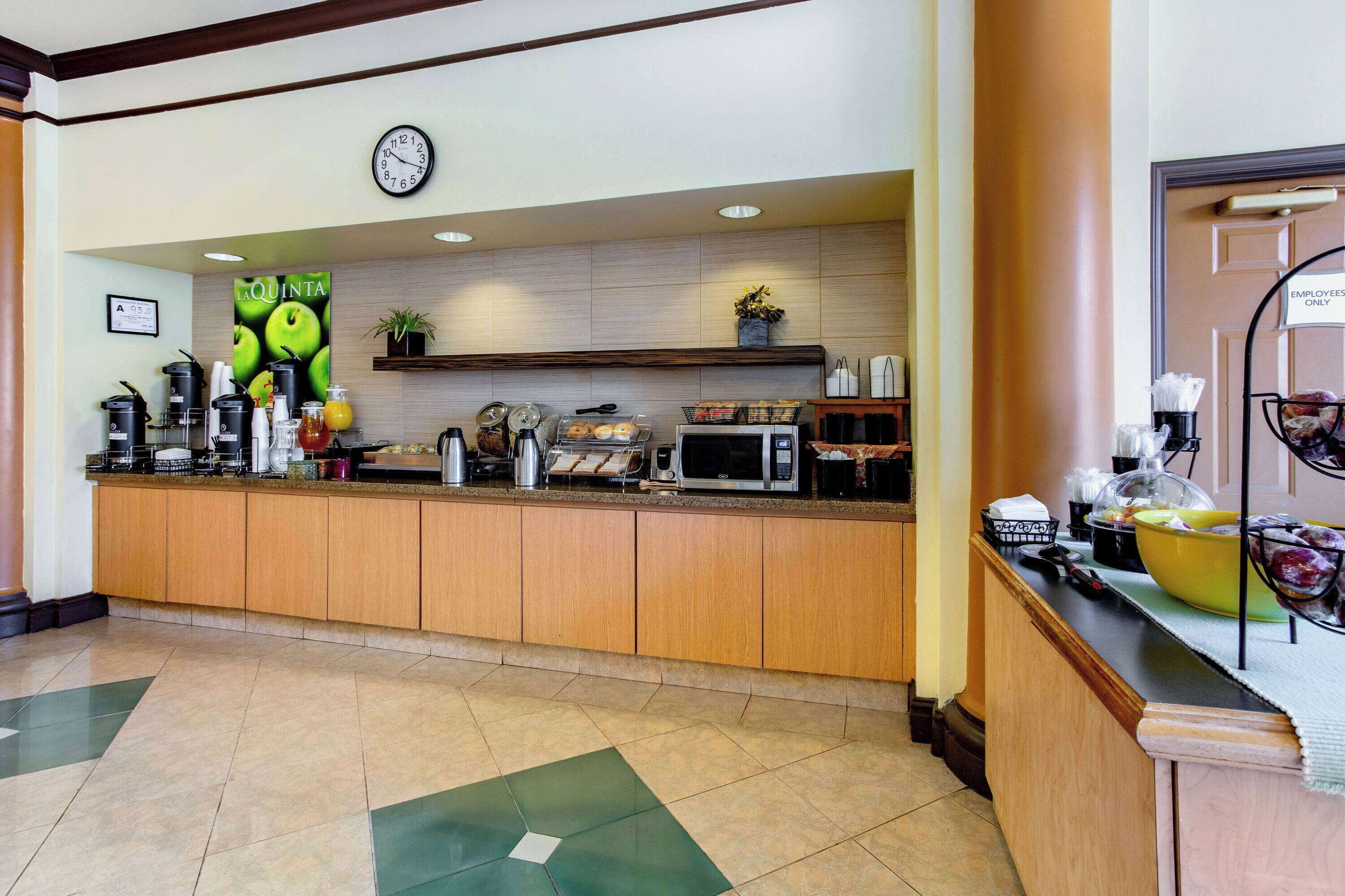 A hotel reception area with a coffee station, a clock, and a sign indicating it's for employees only.