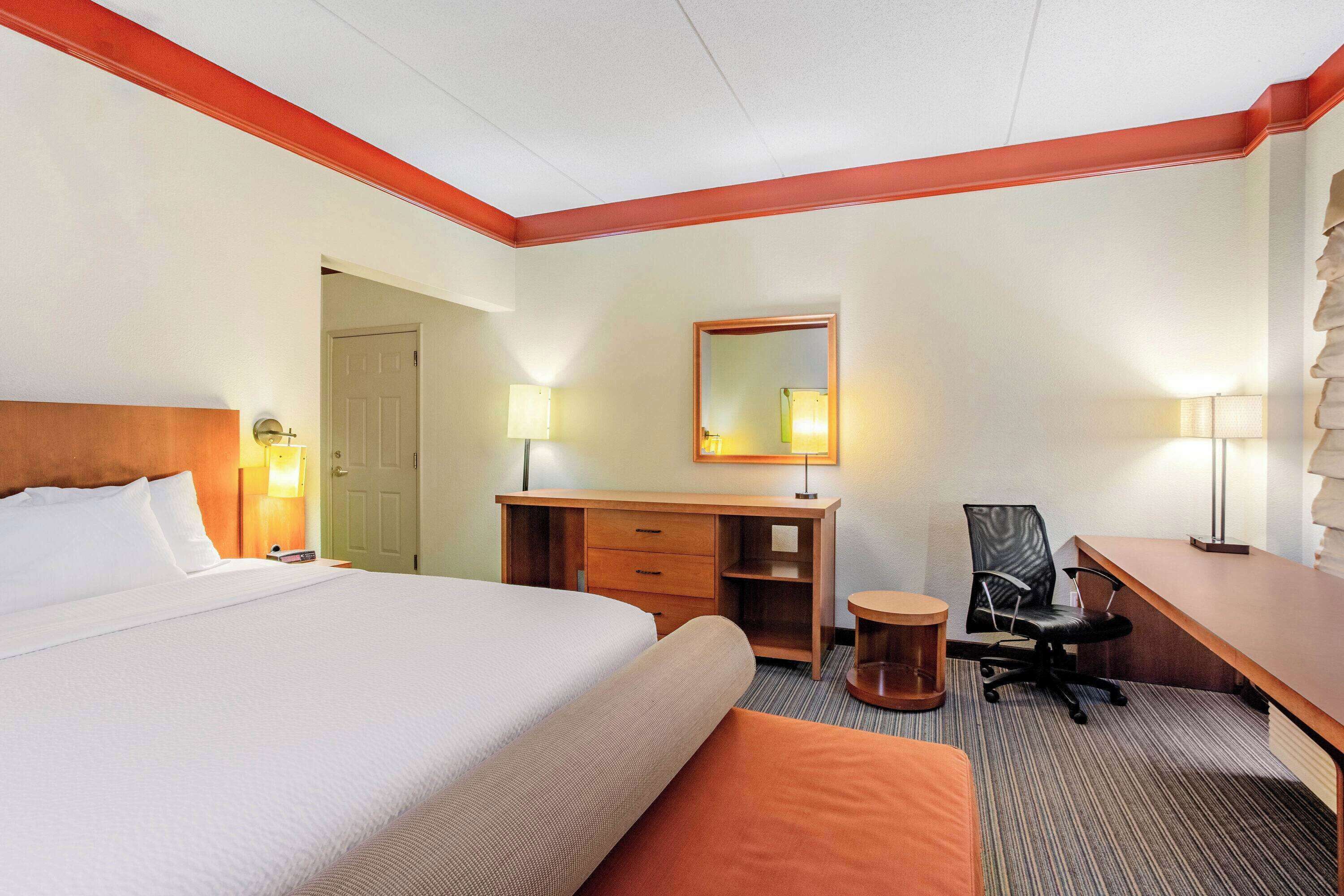 Une chambre d’hôtel avec un grand lit, un bureau en bois, une chaise et une petite table ronde.