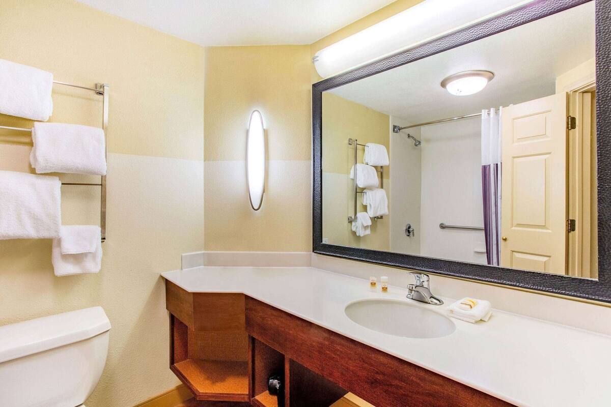 Un baño con un lavamanos blanco, un espejo y un perchero para toallas.