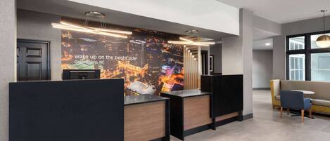 A reception area with a cityscape backdrop, a modern desk design, and a seating area with a sofa and chairs.