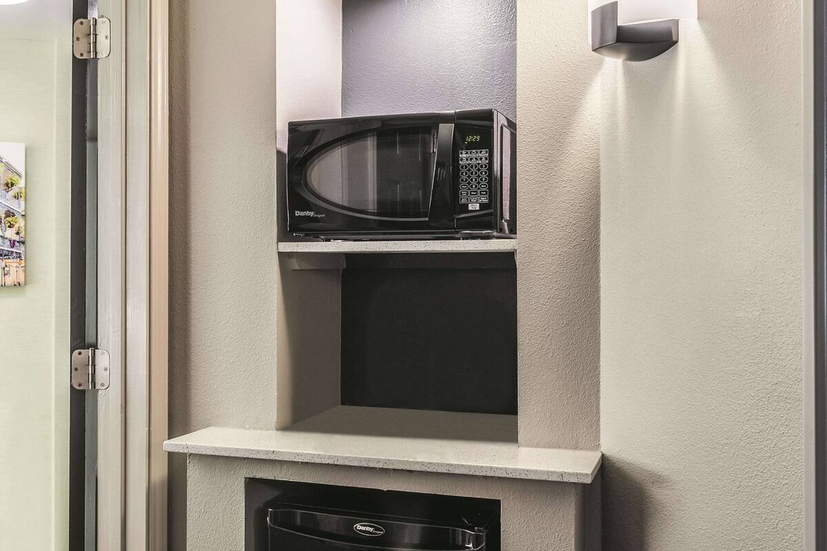 A compact kitchen with a microwave on a shelf, a dishwasher below, and a door with a hinge.