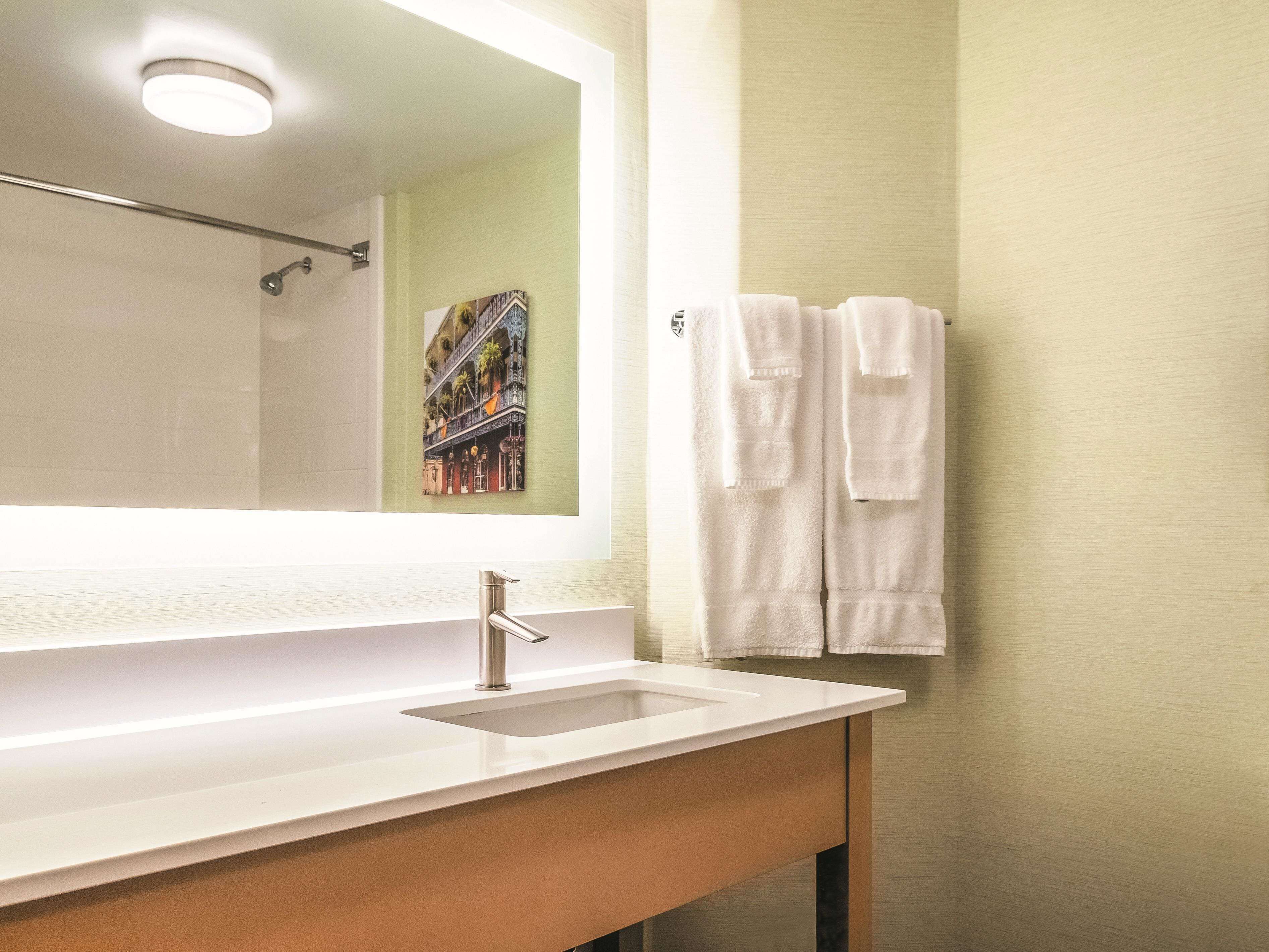 A bathroom with a white sink, a mirror, and two white towels hanging on a towel rack.
