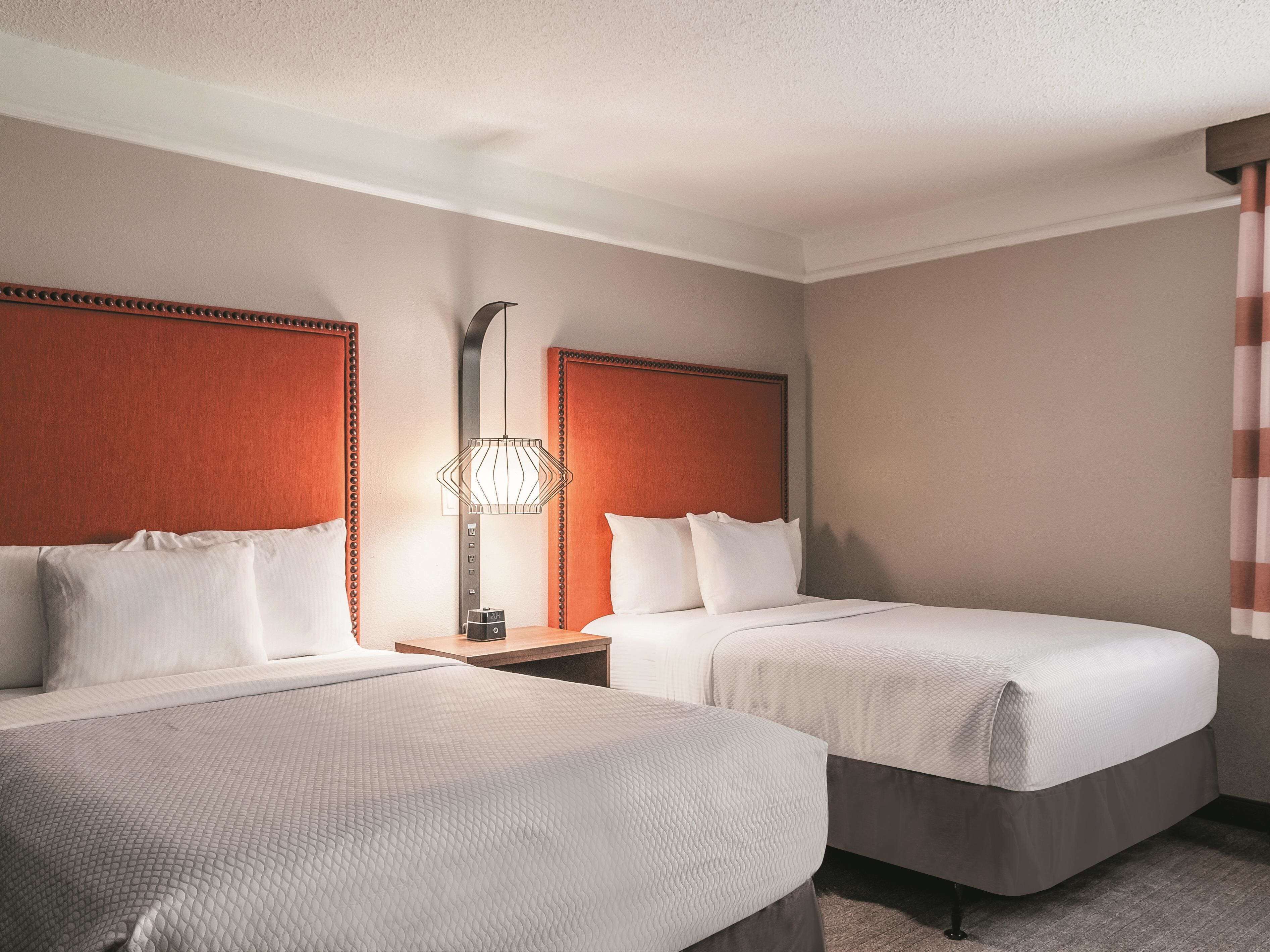 Een hotelkamer met twee bedden, een nachtkastje, een lamp en een spiegel.