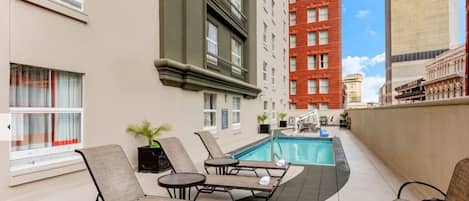 A rooftop pool area with lounge chairs and a small pool.