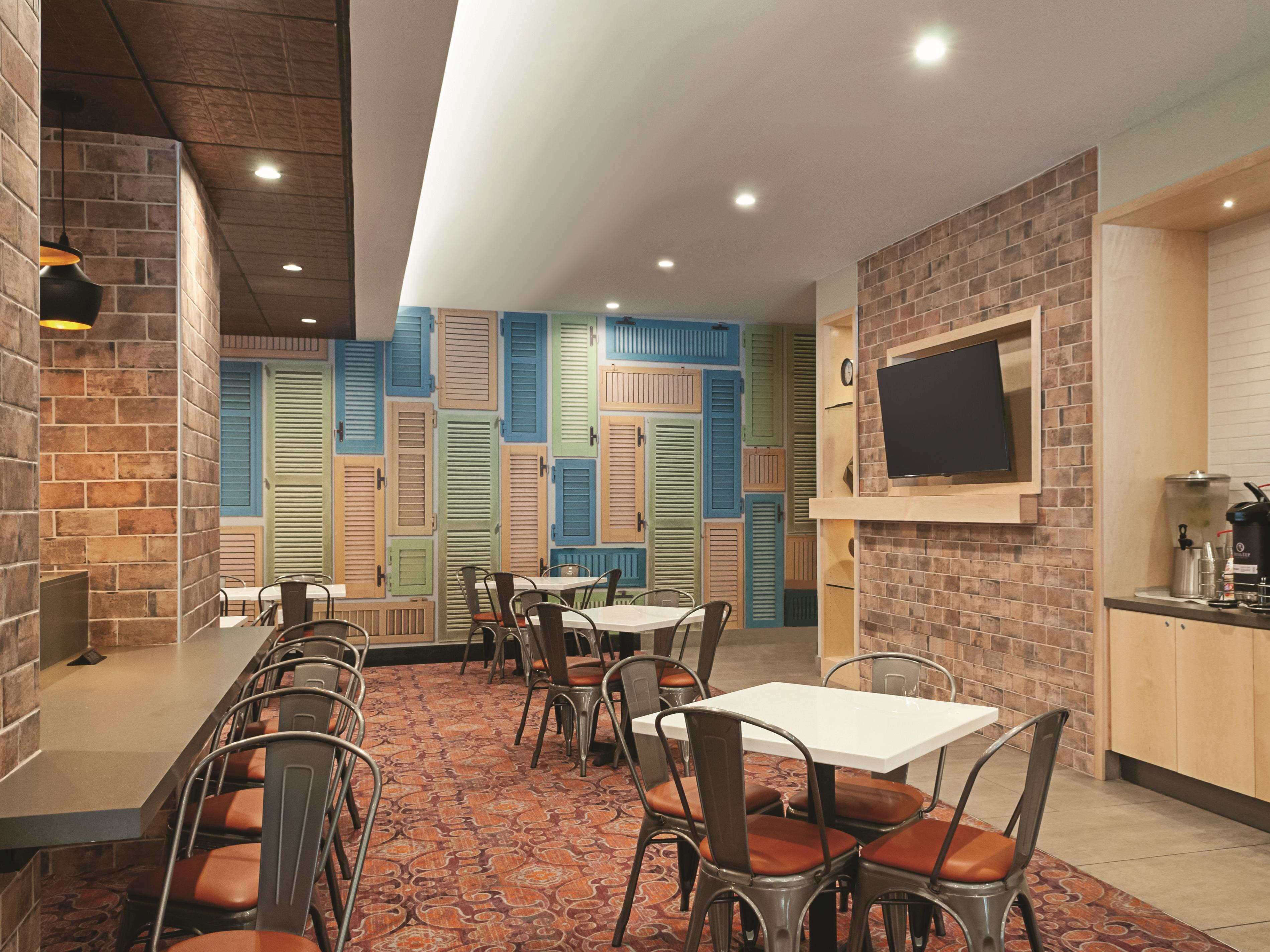 Un restaurante con paredes de ladrillo, contraventanas coloridas y un televisor de pantalla plana montado en la pared.