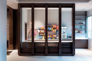 A modern retail space with a variety of packaged goods on shelves, a coffee machine, and a display counter.