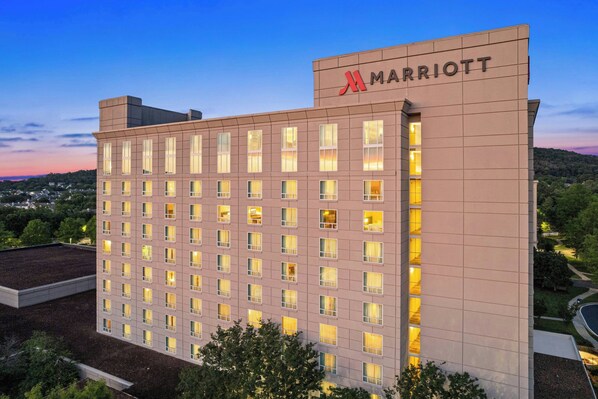Um hotel Marriott com vários andares, fachada plana, diversas janelas e um céu claro ao fundo.