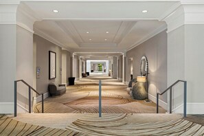 A hotel corridor with a patterned carpet, a staircase, and a view into the distance. - Franklin Marriott Cool Springs (Franklin)