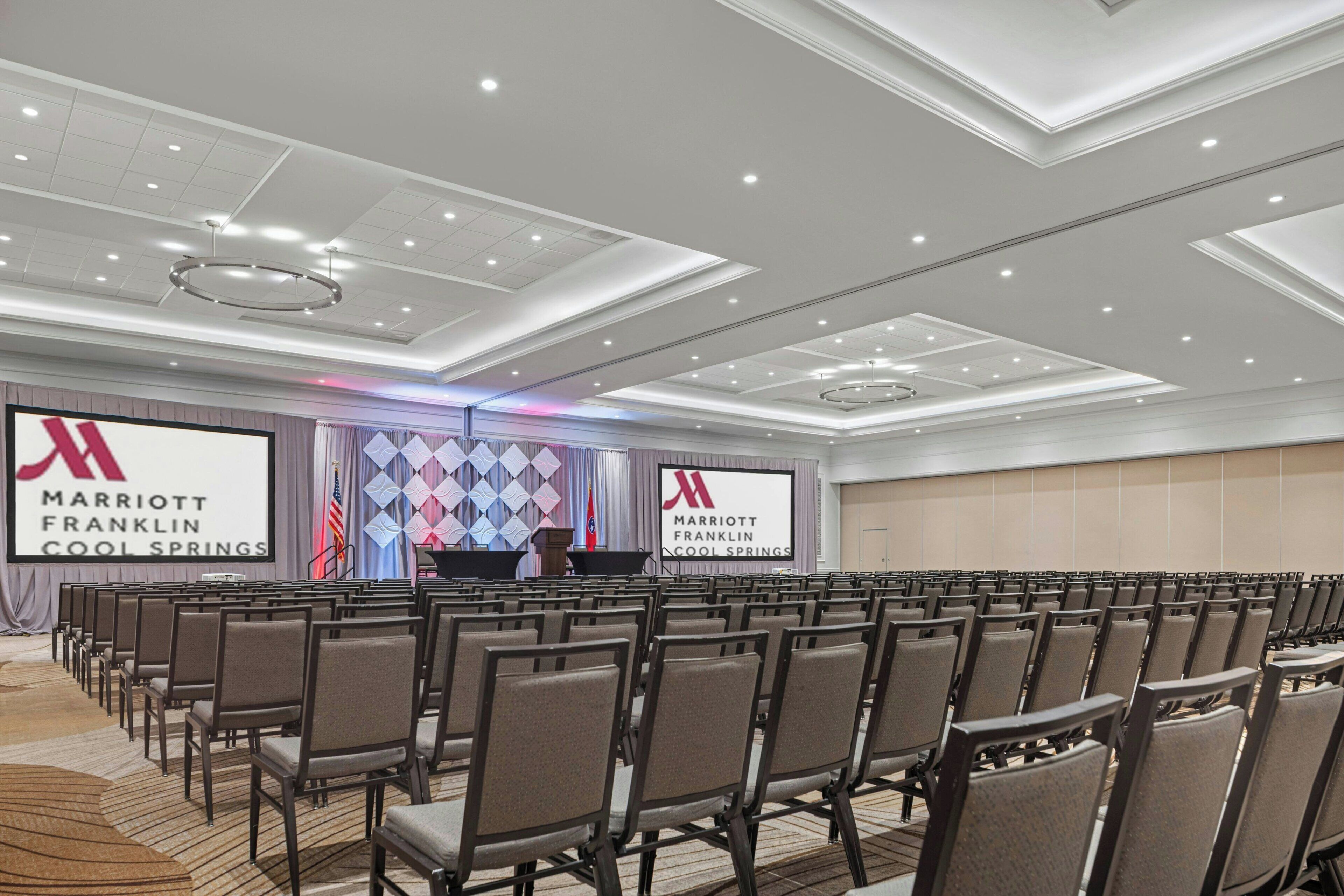 A conference room with rows of chairs, a stage with a podium, and a large screen displaying the Marriott Franklin Cool Springs logo.