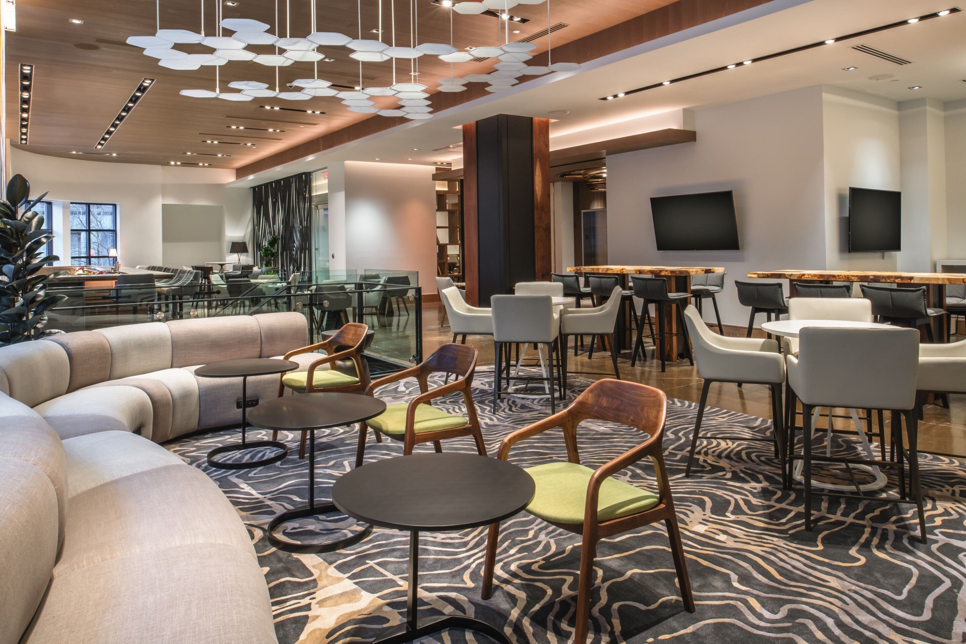 Un espace détente moderne avec un canapé incurvé, des tables rondes et des fauteuils.