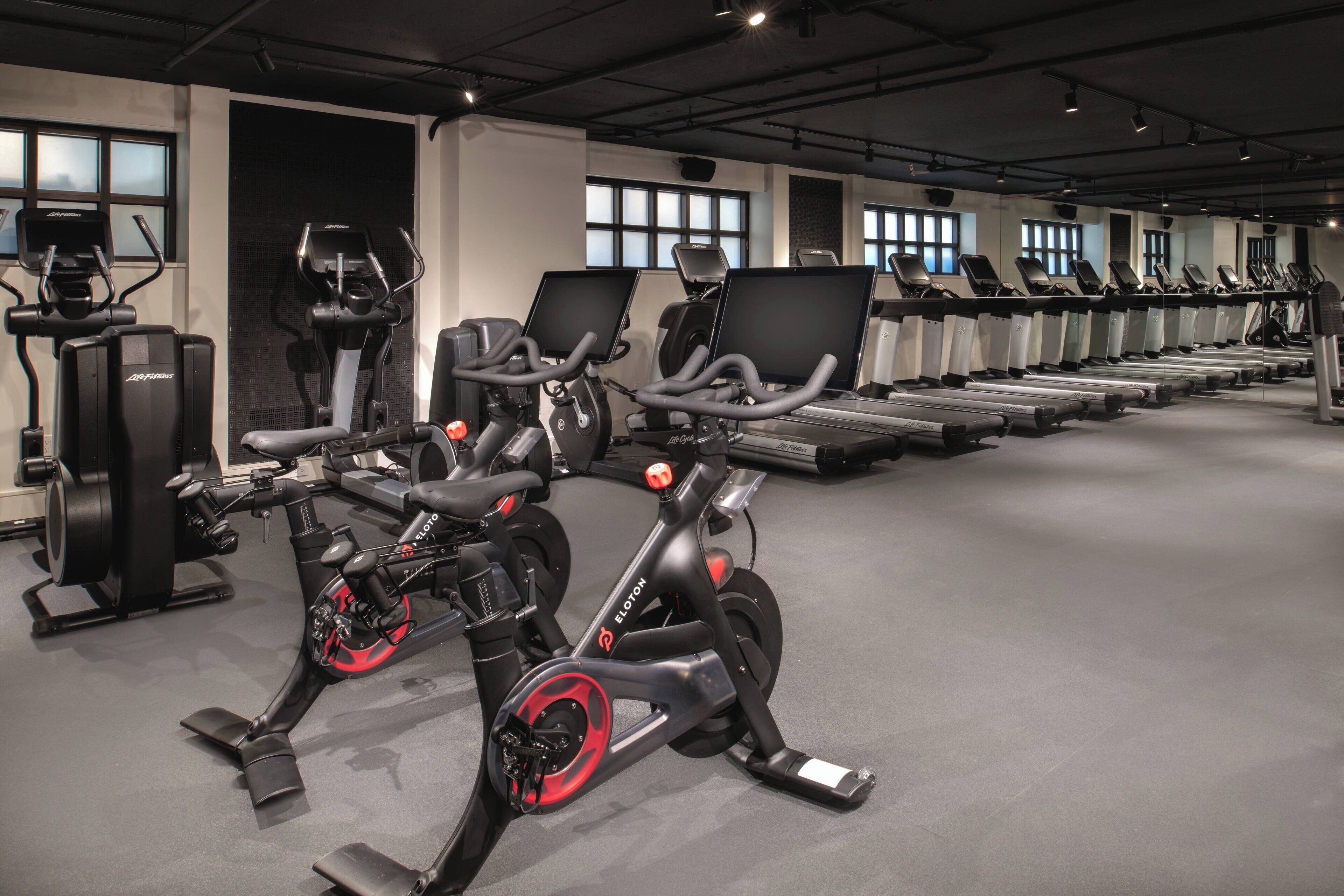 Een fitnessruimte met hometrainers, loopbanden en elliptische trainers.