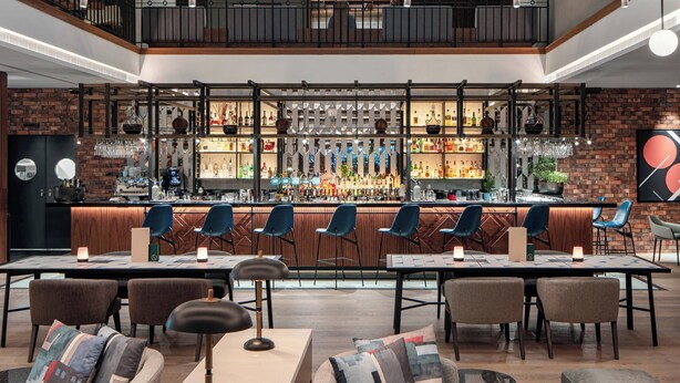 Zona de bar con diversas opciones de asientos, una amplia variedad de botellas y un diseño moderno.