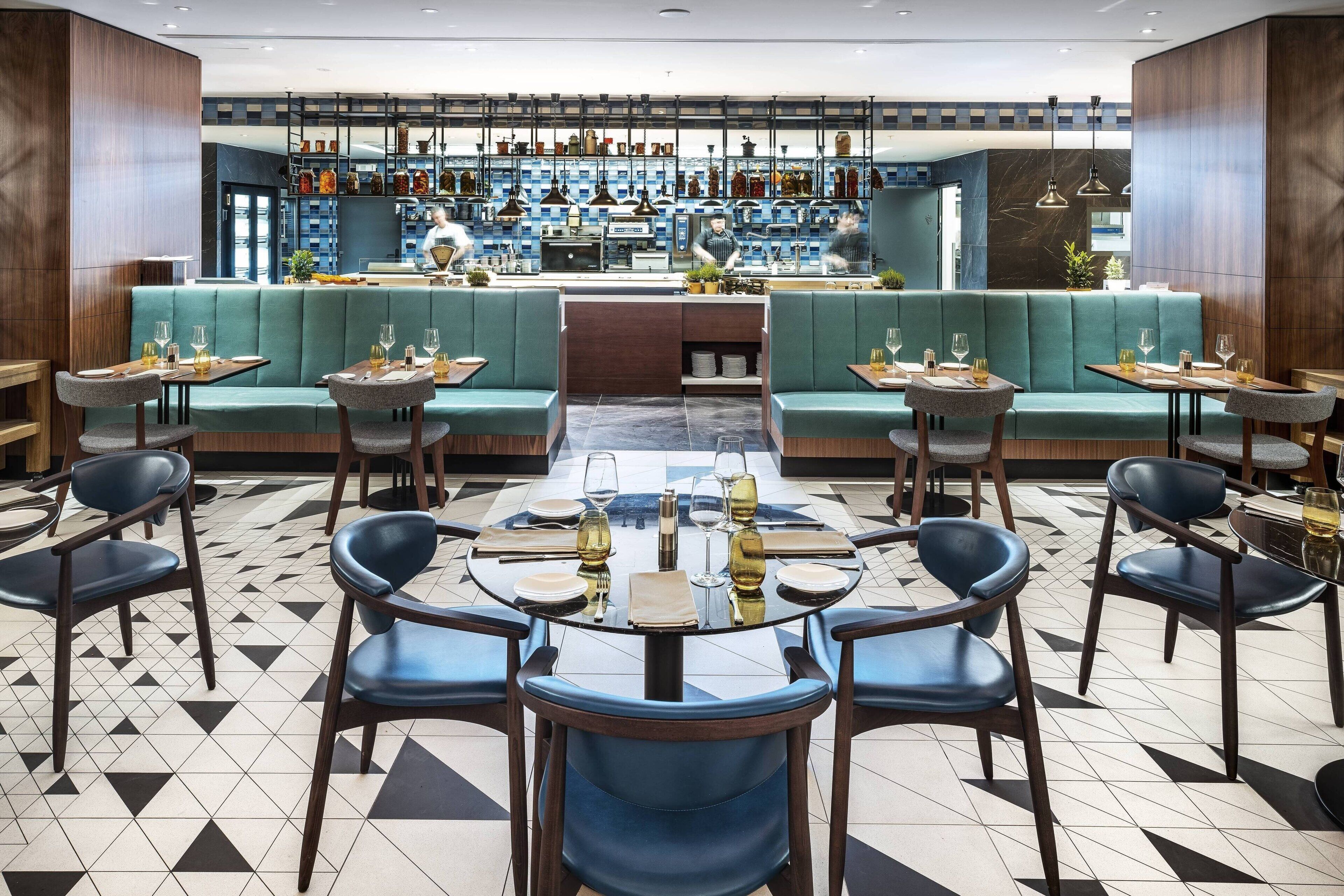 Um restaurante com área de bar, mesas e cadeiras, e piso de azulejos.