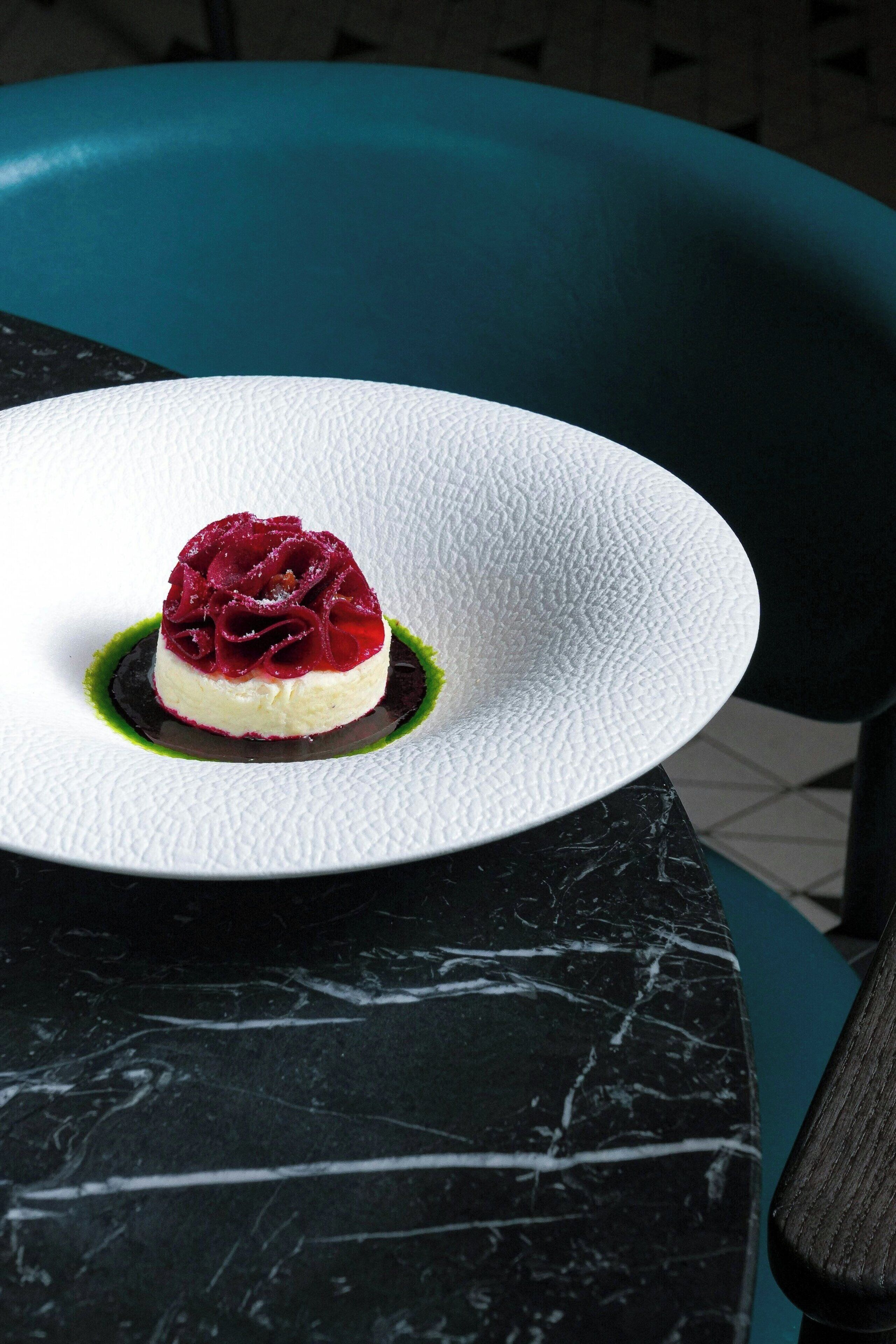 Un postre sobre un plato blanco con superficie texturizada, sobre una mesa de mármol negro.