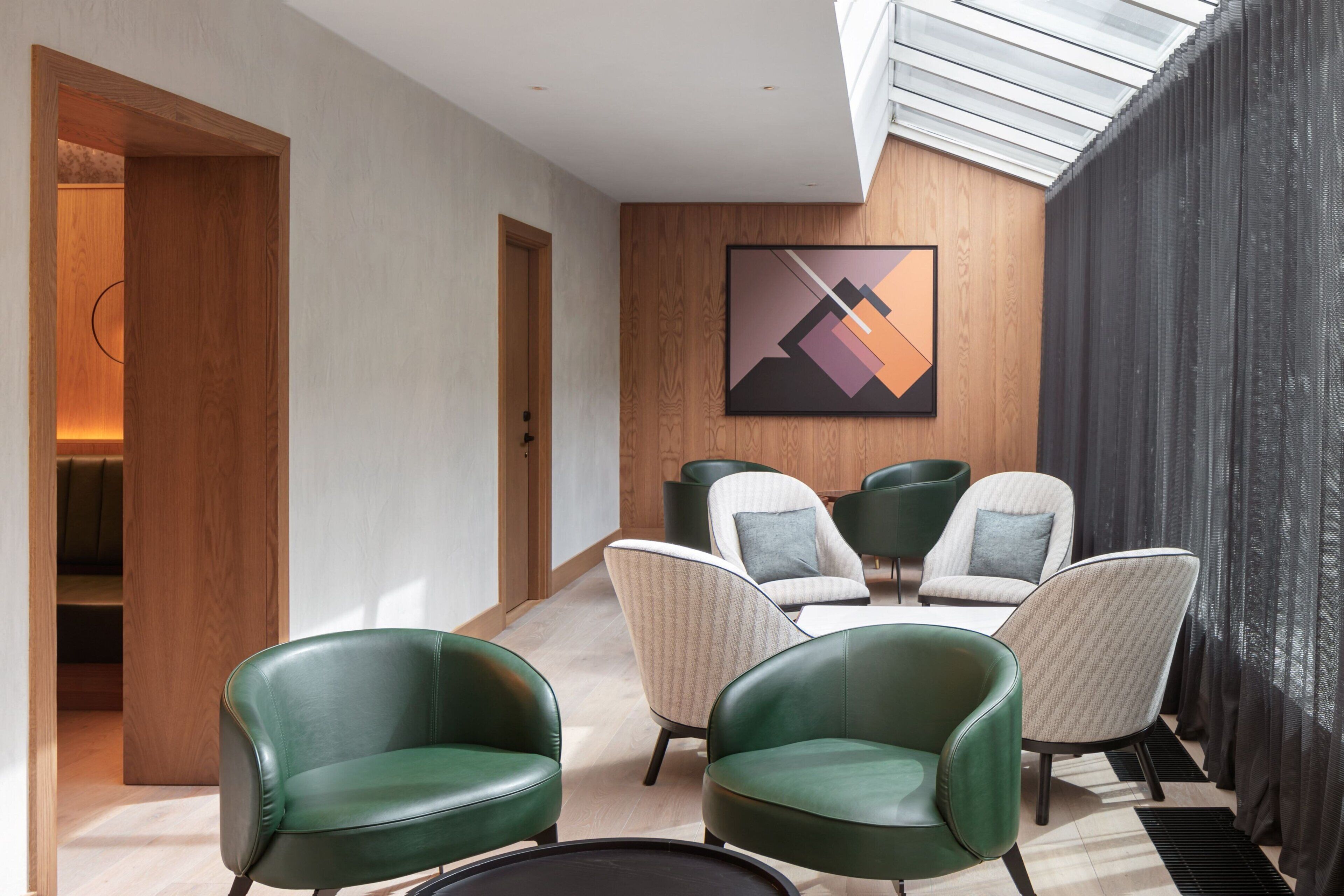 Um interior moderno com área de estar, porta de madeira e uma obra de arte abstrata emoldurada na parede.
