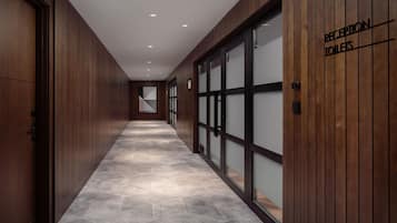 Un pasillo con paneles de madera y suelo de baldosas que conduce a una zona de recepción.