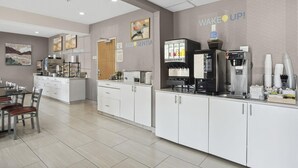 A modern kitchen area with a coffee station, a refrigerator, and a dining table with chairs.