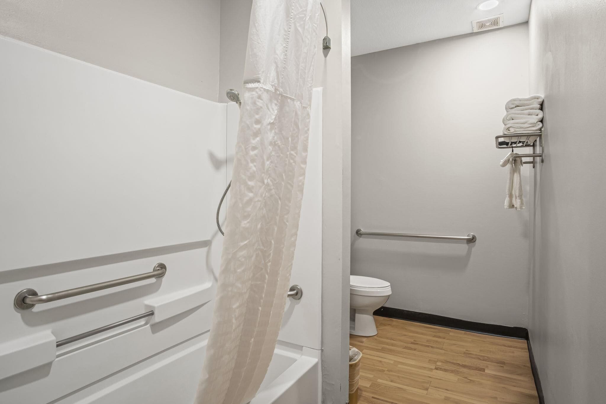 Et badeværelse med et hvidt badekar, et toilet og en håndklæderadiator.