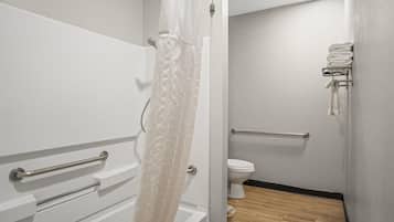 Et badeværelse med et hvidt badekar, et toilet og en håndklæderadiator.