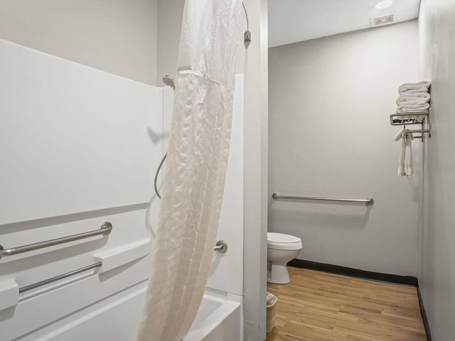 Et badeværelse med et hvidt badekar, et toilet og en håndklæderadiator.