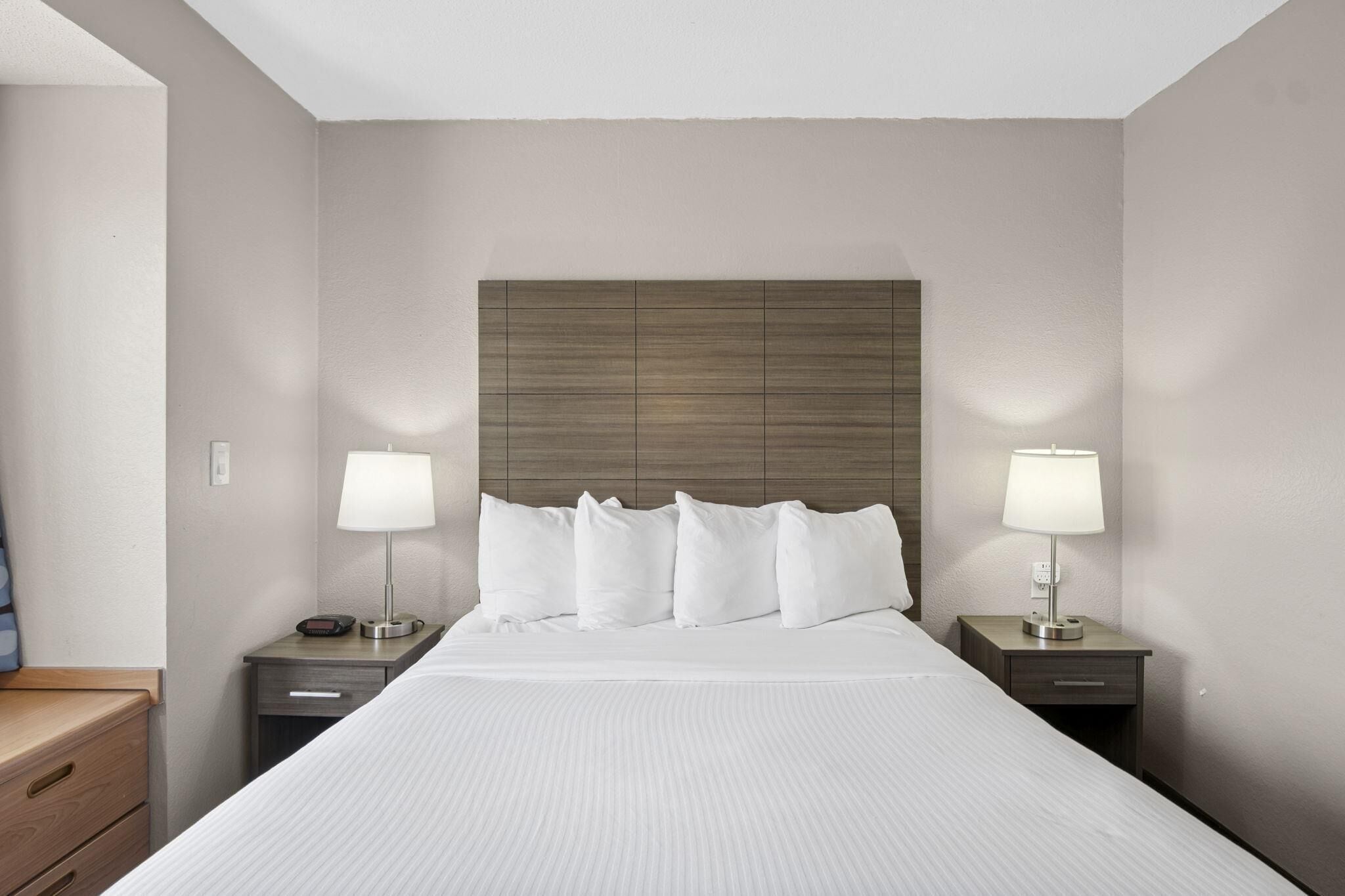 A hotel room with a large bed, two bedside tables with lamps, and a wooden headboard.