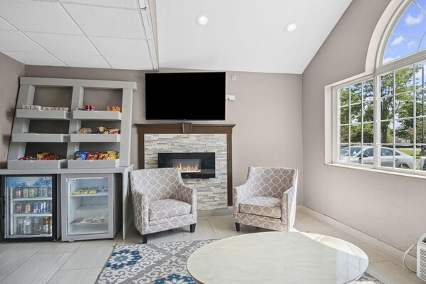 A modern living room with a fireplace, a flat-screen TV, and a mini-fridge.