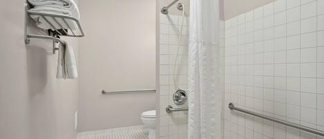 A modern bathroom with a shower, toilet, and towel rack.