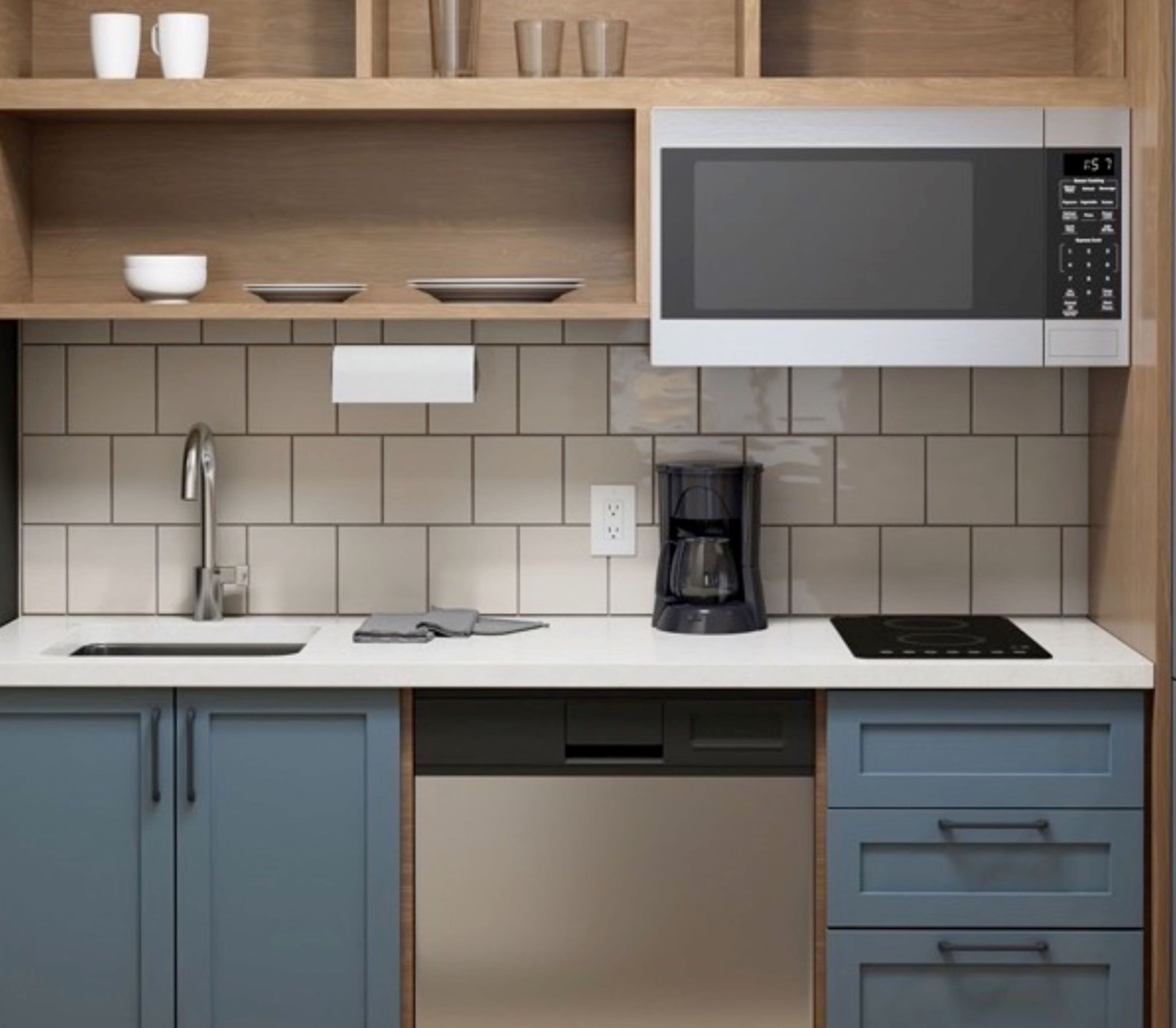 A modern kitchen with a microwave, coffee maker, and a sink.