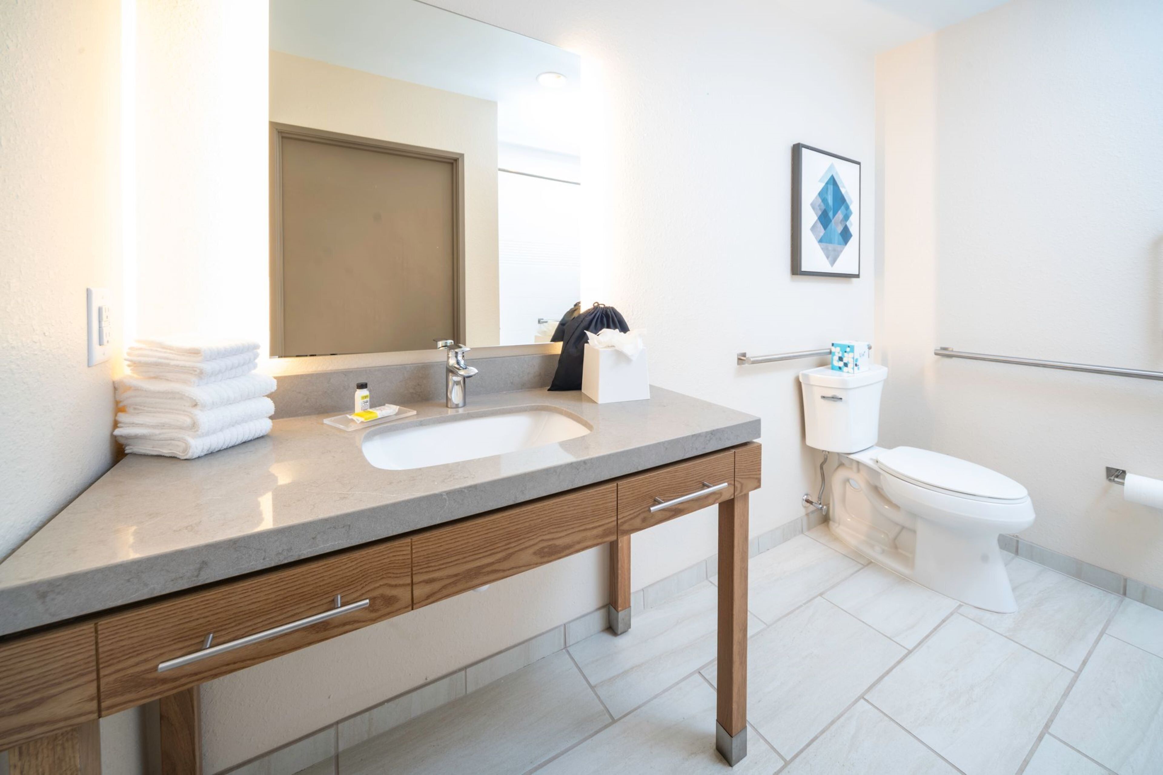 A modern bathroom with a sink, mirror, and toilet.