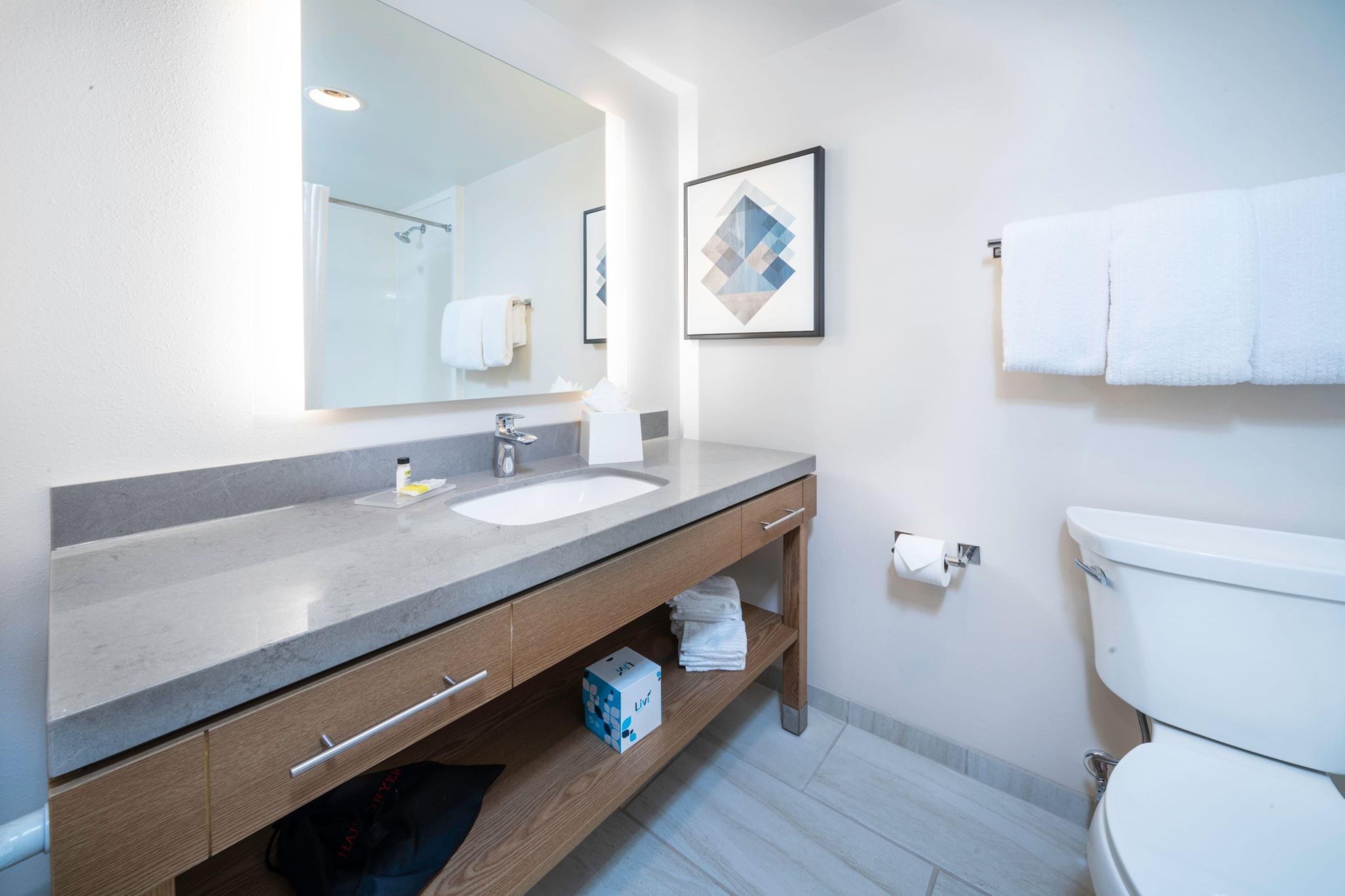 Une salle de bain moderne avec un grand miroir, deux lavabos, des toilettes et un porte-serviettes.