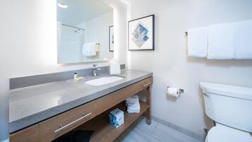 A modern bathroom with a large mirror, two sinks, a toilet, and a towel rack.