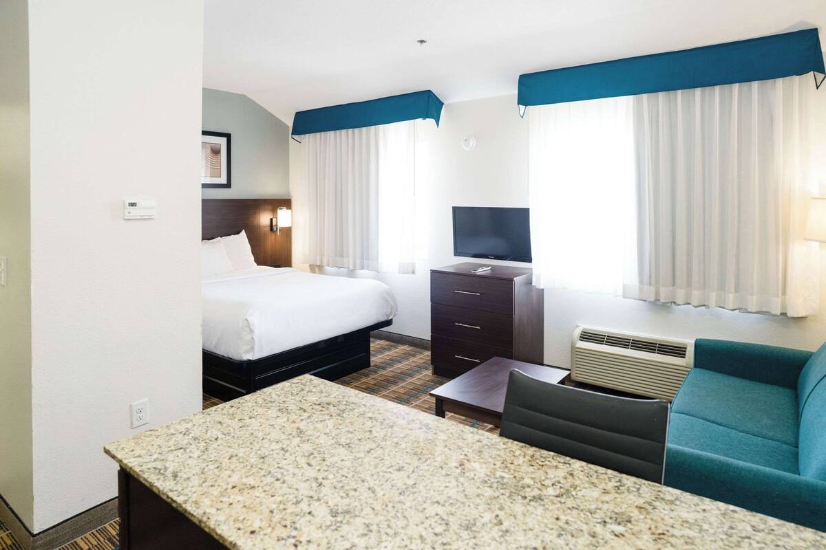 A hotel room with two beds, a television, a desk, and a couch.
