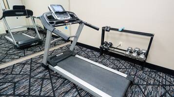 Een sportschool met loopbanden, een hometrainer en gewichten.