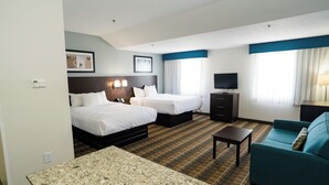 Habitación de hotel con dos camas, un televisor, un sofá y una pequeña mesa.