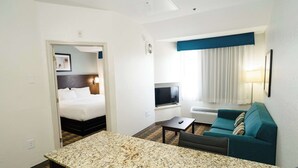 Una habitación de hotel con cama, televisión, sofá, mesa de centro y escritorio.