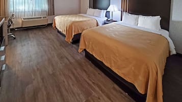 Quarto de hotel com duas camas, uma escrivaninha, uma cadeira, uma televisão e ar condicionado.