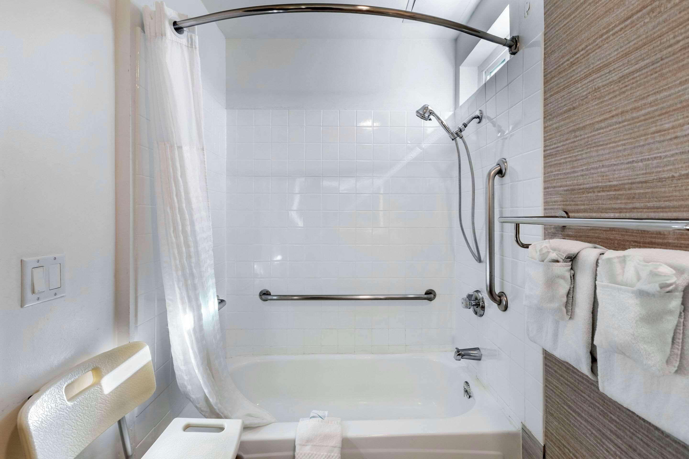Un baño moderno con ducha a ras de suelo, bañera y barra de apoyo.