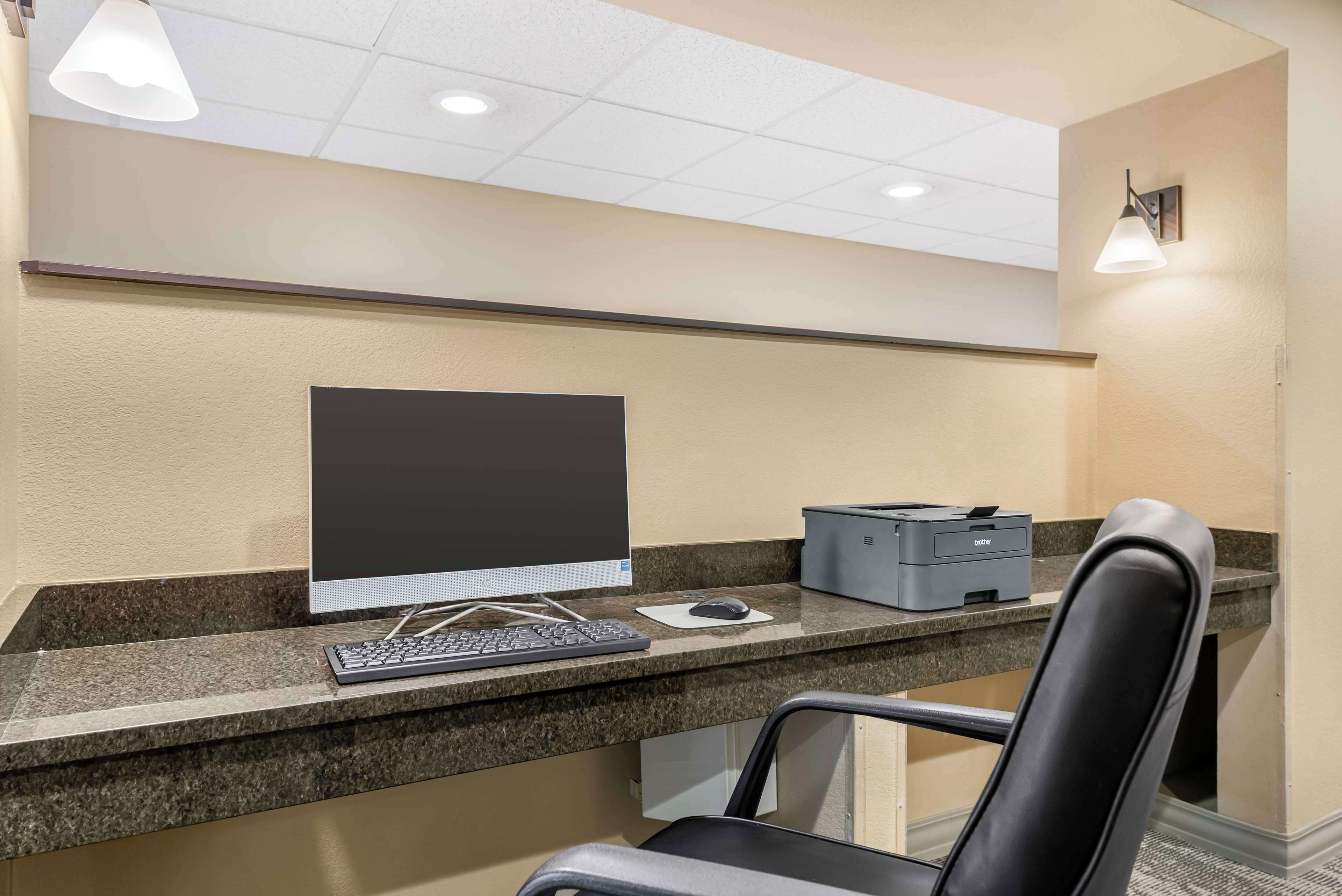 A reception desk with a desktop computer, keyboard, mouse, and printer.