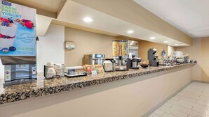A hotel breakfast area with a self-serve station, including a yogurt dispenser, coffee maker, and various food containers. - Best Western Executive Inn & Suites (Colorado Springs)