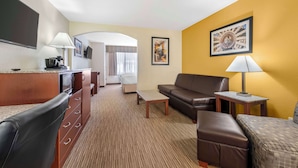 A hotel room with a kitchenette, a sofa, a coffee table, a TV, and a framed picture on the wall. - Best Western Executive Inn & Suites (Colorado Springs)