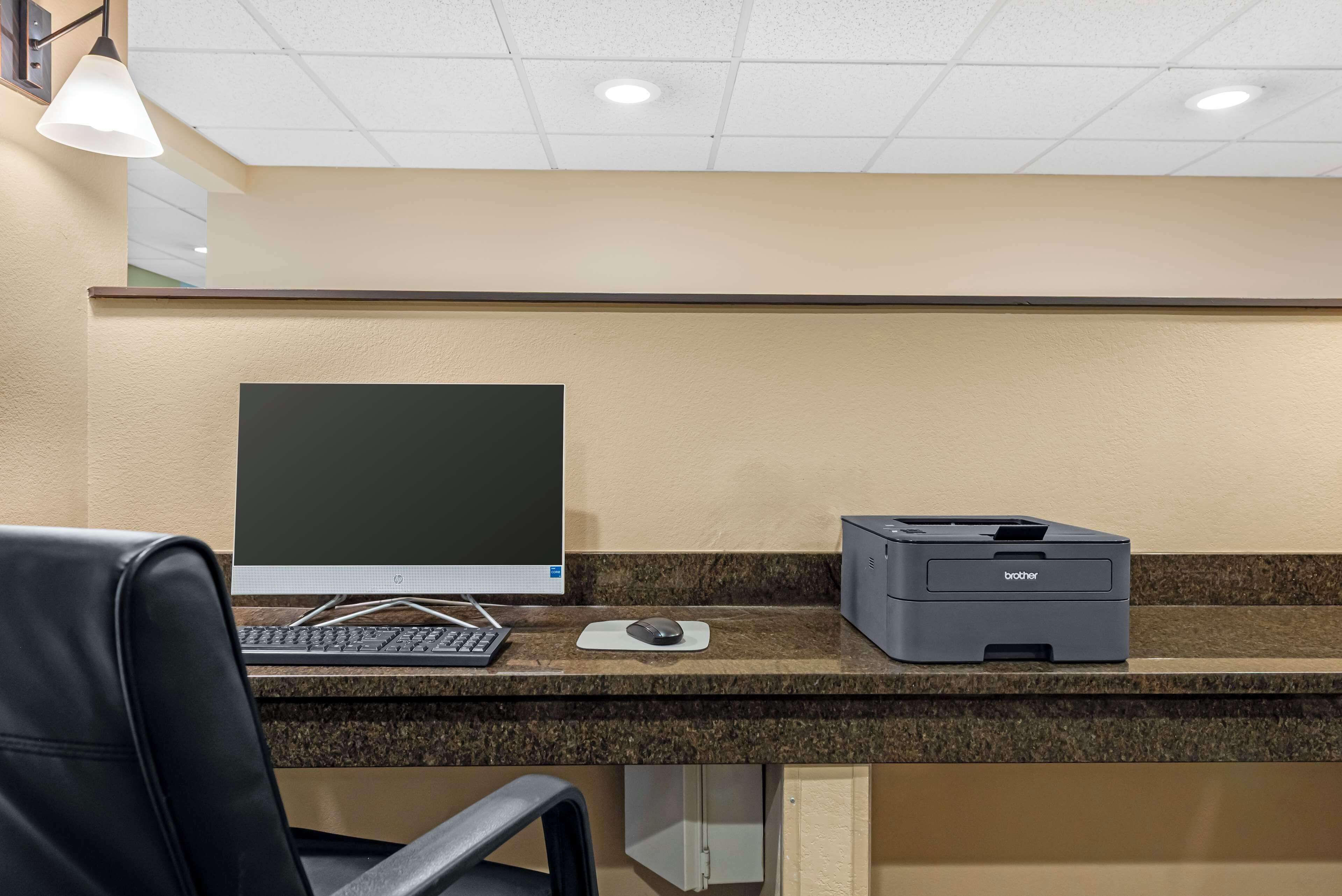 A desk with a desktop computer, a printer, and a mouse.