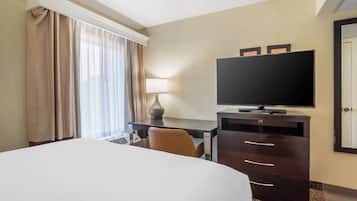 Une chambre d’hôtel avec un grand lit, un bureau doté d’un téléviseur à écran plat, une lampe et une commode.